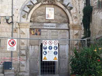 ...ma a interrompere drasticamente l'eleganza dell'ingresso, interviene un�insolita e moderna insegna bianca che recita "riparazioni frigoriferi", sovrastata da un piccolo quadro contenente l'immagine di San Nicola